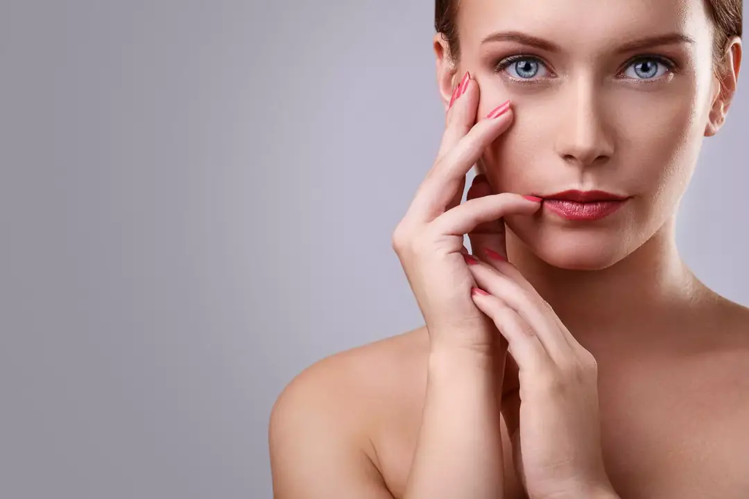 Woman with glowing skin touching her cheek