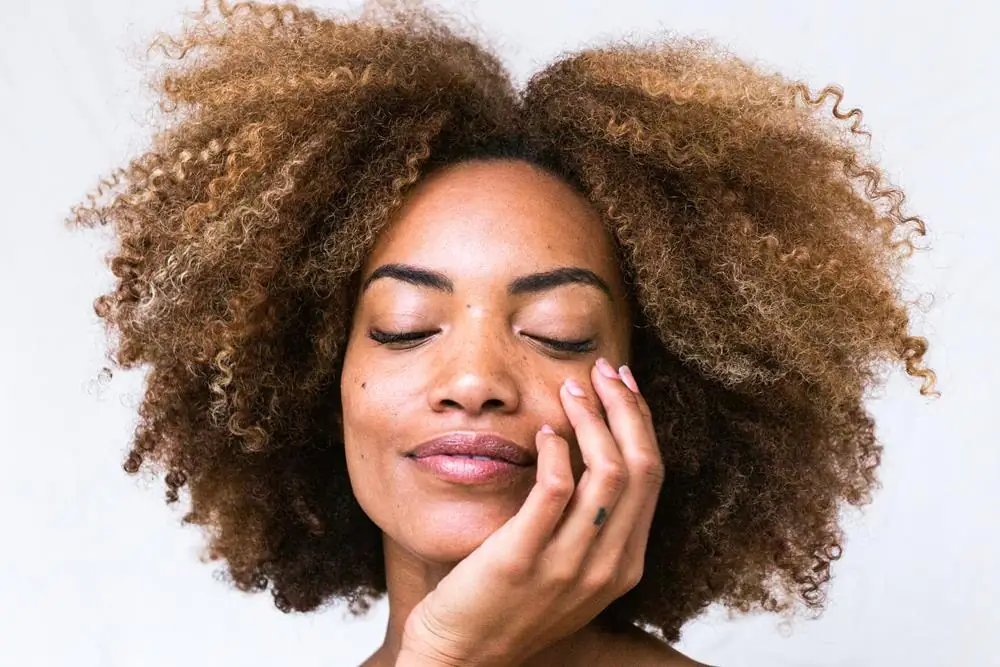 Woman with natural curls smiling with her eyes closed